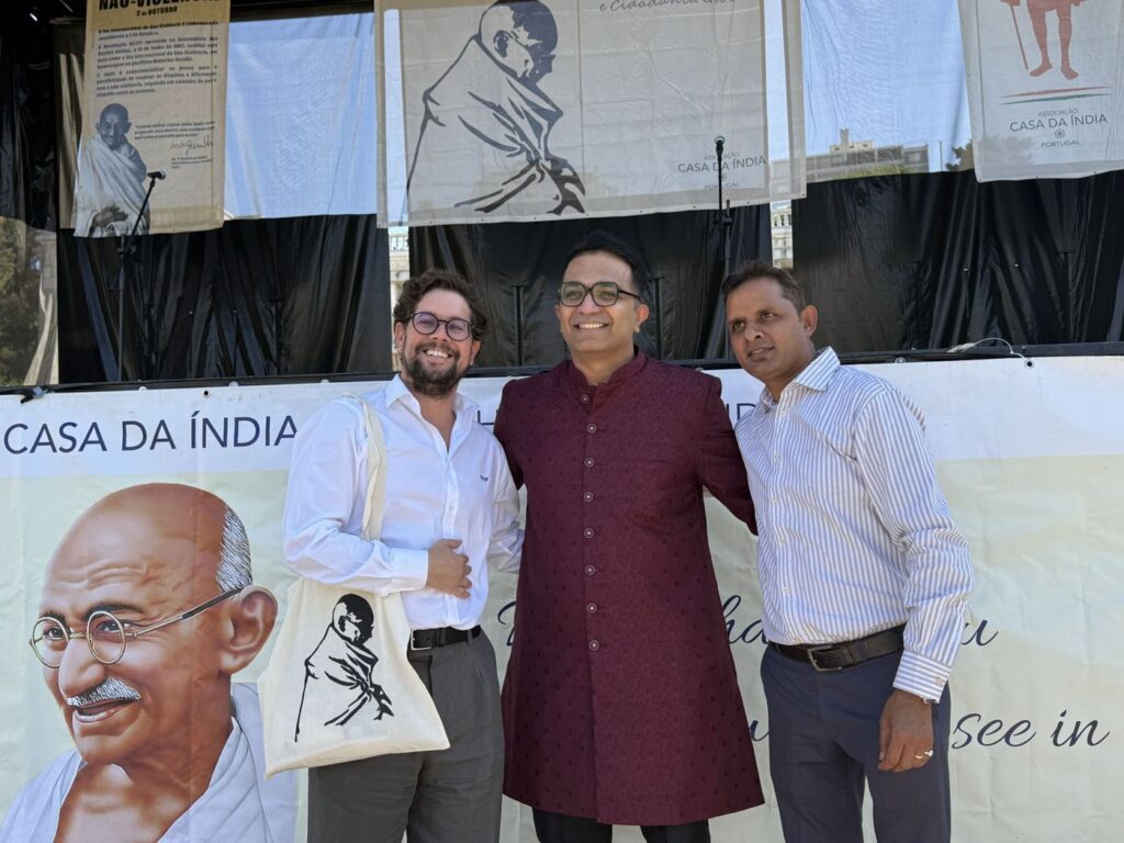 TLG Foundation representatives posing with a Mahatma Gandhi tote bag at the Casa da Índia stage, Festival Gandhi 2026
